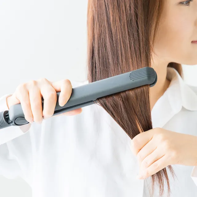 ヘアアイロンを使用している女性の写真